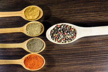 Spoons with the different spices on dark wooden table. Top view