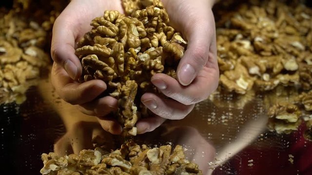 A woman gathers nuts from a mirror table, slow motion