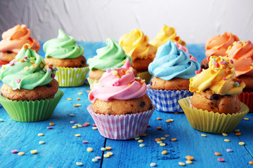 Tasty cupcakes on wooden background. Birthday cupcake in rainbow colors