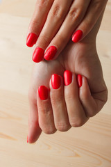Beautiful female finger nails with red nail closeup on petals. Perfect manicure