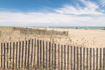 Obraz premium Beach with colorful umbrellas, wooden fences and wildlife.