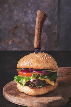Homemade hamburger with knife  on dark background closeup