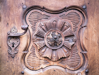 Detail of a carved wooden portal with wrought iron handle.