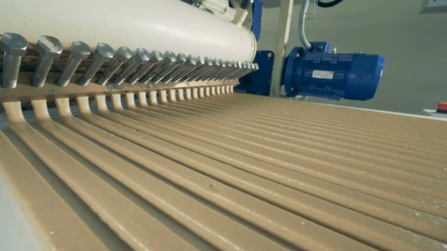 Long parallel lines of candy cream are flowing along the conveyor belt