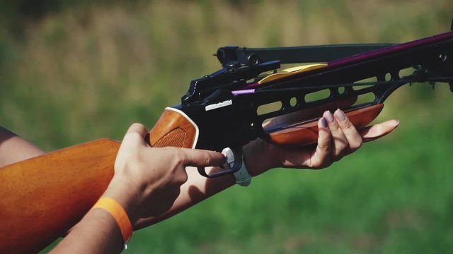 blond girl is shooting an arrow from a crossbow. Slow motion. Closeup.