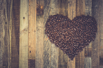 Coffee beans in a shape of heart on wooden background