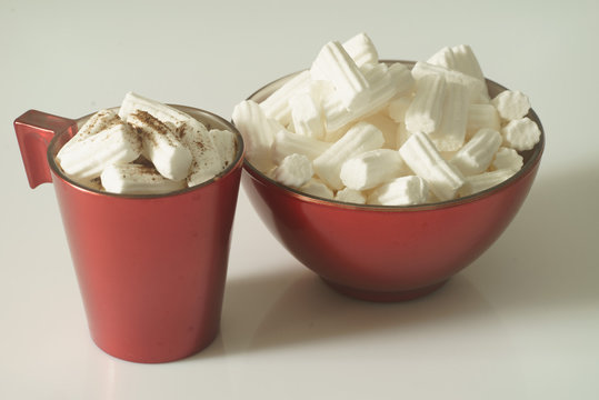A Cup of coffee or hot chocolate with marshmallows and a red plate on a white background. Close up. Christmas photo. 