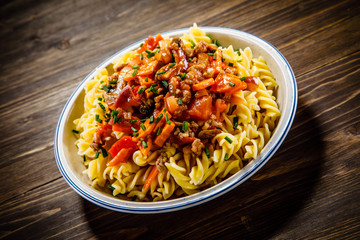 Pasta with tomato sauce and vegtables on wooden table 