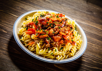 Pasta with tomato sauce and vegtables on wooden table 