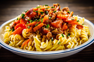 Pasta with tomato sauce and vegtables on wooden table 