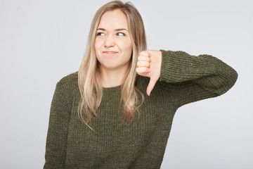 Studio portrait of annoyed and disgusted young European woman wearing stylish clothing expressing...