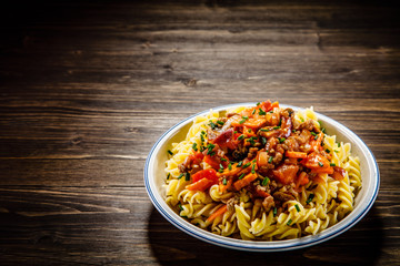 Pasta with tomato sauce and vegtables on wooden table 