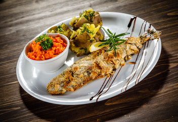 Fish dish - roast trout with almonds and vegetables on wooden table