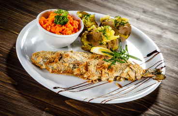 Fish dish - roast trout with almonds and vegetables on wooden table