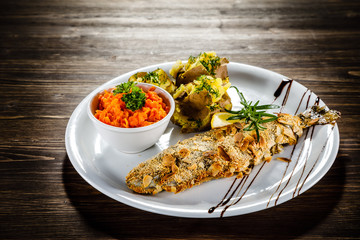 Fish dish - roast trout with almonds and vegetables on wooden table