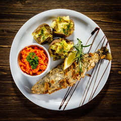 Fish dish - roast trout with almonds and vegetables on wooden table