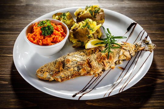 Fish dish - roast trout with almonds and vegetables on wooden table
