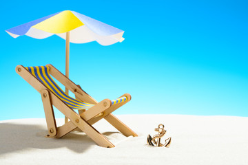 A chaise longue under an umbrella on the sandy beach, sky with copy space