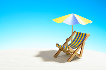 A chaise longue under an umbrella on the sandy beach, sky with copy space