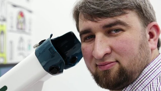 Patient in ophthalmology clinic. Man looks at the camera near apparatus for the treatment of spasm of accommodation, amblyopia and binocular vision disorders