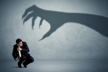 Business person afraid of a big monster claw shadow concept © ra2 studio