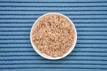 Buckwheat porridge in a white bowl on a blue fitness mat
