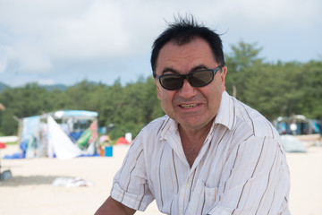 Elderly Man in sunglasses and a light shirt on the beach