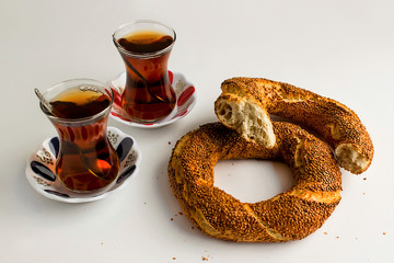 Traditional Turkish crispy bagel (simit) with two transparent,classic glass tea on the white background.Close up taken,isolated.