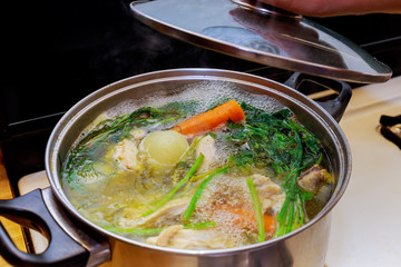 Ingredients for preparing chicken bone broth in a pot chicken, onions, celery root, carrots, parsley - obrazy, fototapety, plakaty