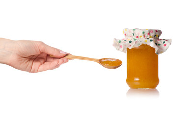 Orange apricot peachy jam in a jar cover wooden spoon in hand