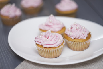 four cupcakes on grey wooden table, three cupcakes on oval white plate.
