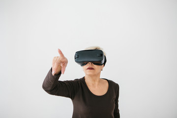 An elderly woman in virtual reality glasses. An elderly person using modern technology.