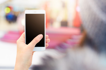 Shot of unrecognizable woman holds modern cell phone with blank black screen watches video or views photos, surfes social media websites, connected to wireless internet. Advertising concept.