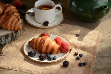 The freshly baked croissants for breakfast with berries and green tea 