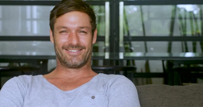 Handsome man sitting with a scruffy beard smiling and looking at the camera