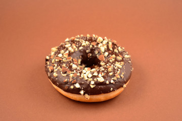 Chocolate donut with nuts stock images. Donut on a brown background. Donut with chocolate frosting and nuts