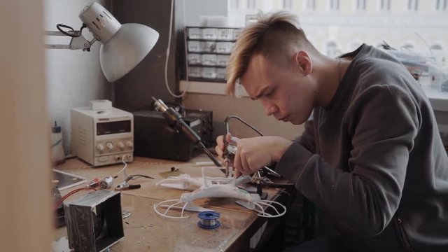Technician with a soldering iron is working on a drone
