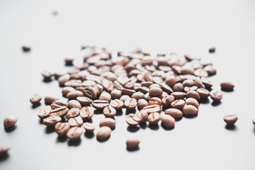 The grains of roasted coffee are scattered on a black matte surface