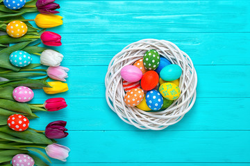 Easter eggs with colorful tulips on wooden background, easter holiday concept.
