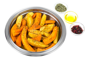 Raw potato slices and pumpkin with spices in metal bowl