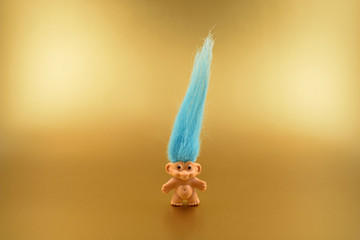 Troll figure stock images. Elf on a golden background. Troll with blue hair. Troll toy images - obrazy, fototapety, plakaty