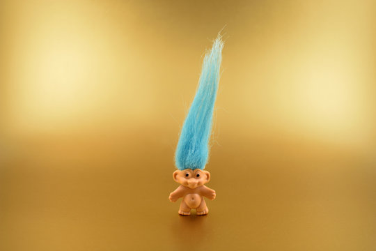 Troll figure stock images. Elf on a golden background. Troll with blue hair. Troll toy images