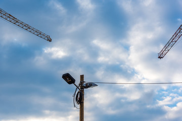 two construction cranes a street lighting and a cable