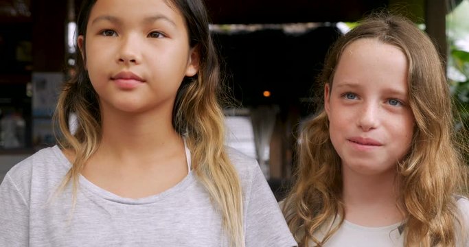 Two young girls standing looking at the camera talking and smiling