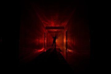 Creepy silhouette in the dark abandoned building. Dark corridor with cabinet doors and lights with...