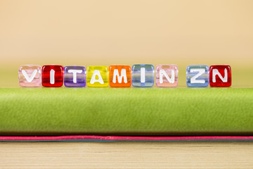 color cube figure with word vitamin zn on green book