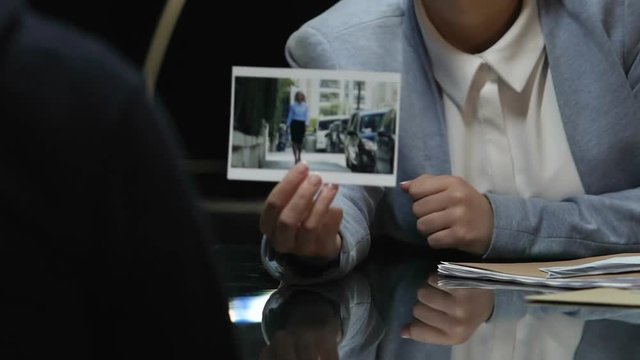 Cop showing to criminal victim photo and checking reaction, body language