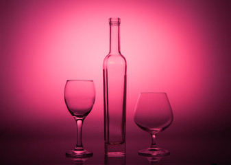 Empty bottle and glasses on a rad graded background