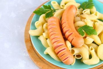 Pasta Cavatappi or Cellentani with sausages on a gray table.