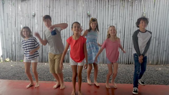 Happy boys and girls age 11 - 13 jumping up together in slow motion